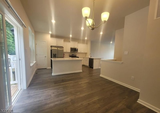 kitchen with pendant lighting, appliances with stainless steel finishes, white cabinetry, dark hardwood / wood-style flooring, and a chandelier