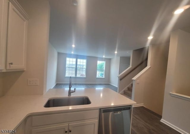 kitchen with sink, white cabinetry, stainless steel dishwasher, dark hardwood / wood-style floors, and kitchen peninsula