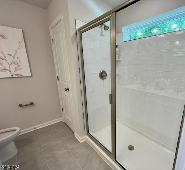 bathroom with tile patterned floors, toilet, and a shower with shower door