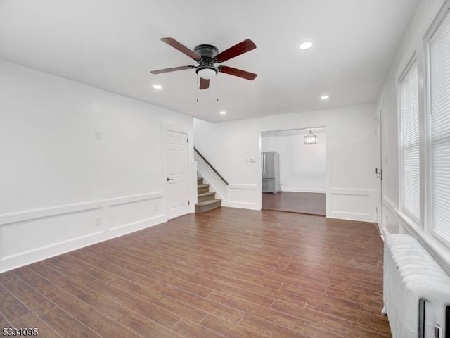 unfurnished living room featuring ceiling fan, dark wood-type flooring, and radiator