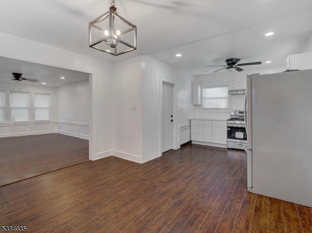 kitchen featuring ceiling fan with notable chandelier, appliances with stainless steel finishes, dark wood-type flooring, white cabinetry, and hanging light fixtures