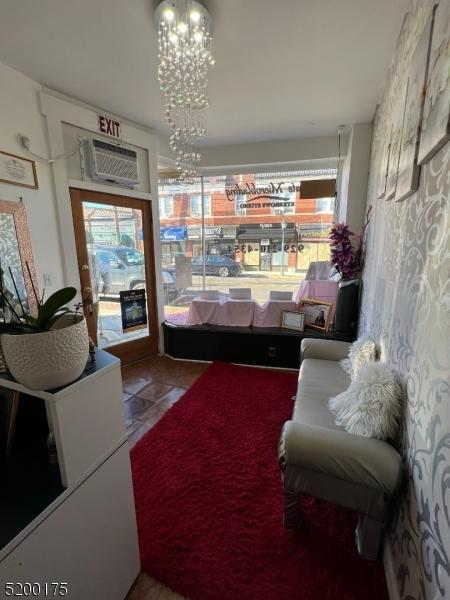 sitting room with an inviting chandelier and a wall mounted air conditioner