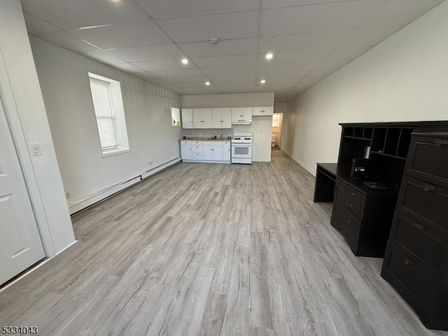 unfurnished living room featuring a drop ceiling, a baseboard heating unit, and light wood-type flooring