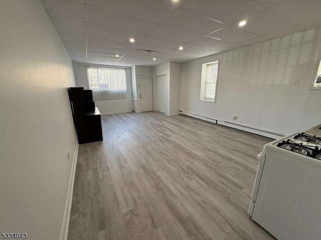 unfurnished living room with baseboard heating, a drop ceiling, and light hardwood / wood-style flooring