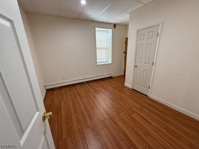 spare room with a baseboard radiator, light hardwood / wood-style flooring, and a paneled ceiling