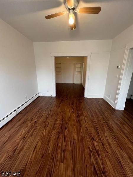 unfurnished room featuring ceiling fan, a baseboard radiator, and dark hardwood / wood-style floors