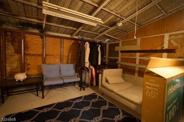 interior space with wooden walls, lofted ceiling, and concrete flooring