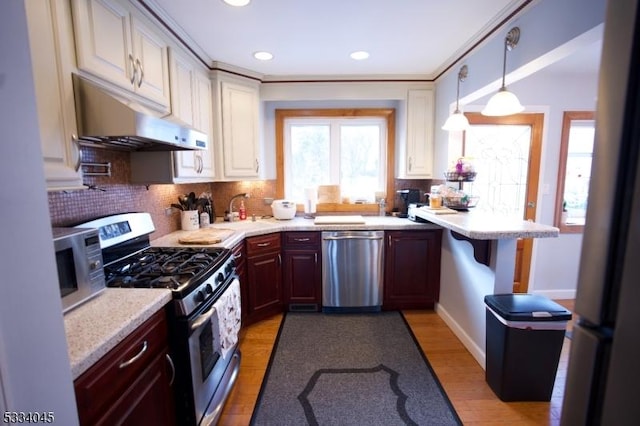 kitchen featuring sink, a breakfast bar area, appliances with stainless steel finishes, dark brown cabinets, and decorative light fixtures