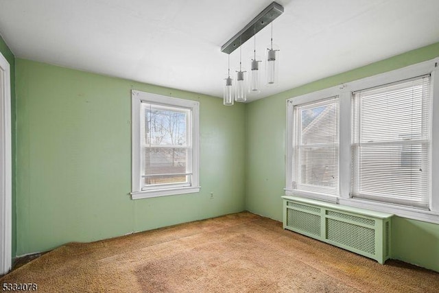 unfurnished room featuring radiator heating unit and light carpet