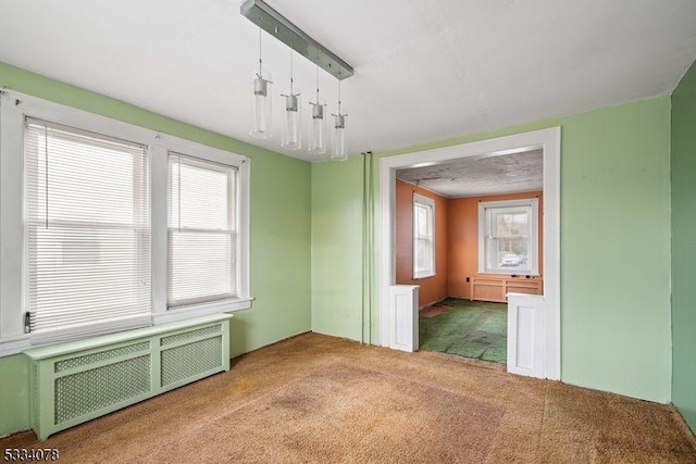 unfurnished room featuring carpet and radiator