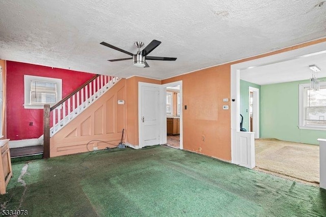 unfurnished living room featuring ceiling fan, carpet, and a textured ceiling