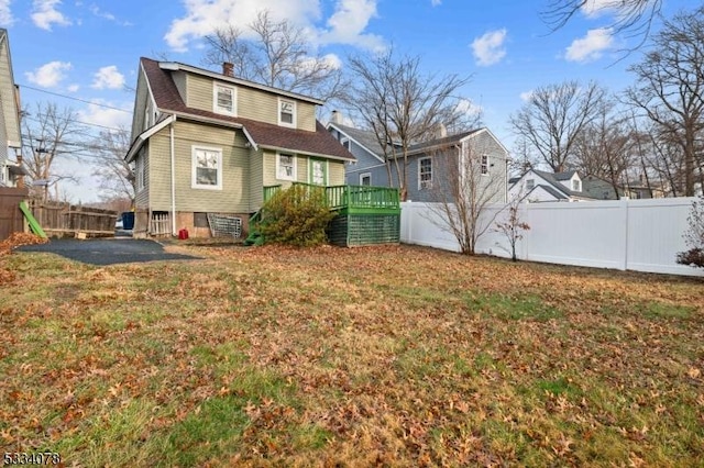 back of property with a wooden deck and a yard