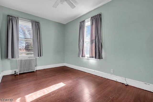 spare room featuring dark wood-type flooring, radiator heating unit, and ceiling fan