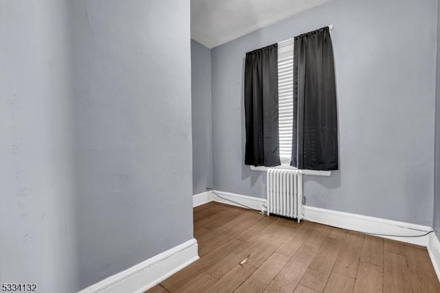 unfurnished room with hardwood / wood-style flooring and radiator heating unit