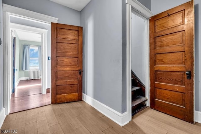 corridor featuring radiator heating unit and light hardwood / wood-style floors