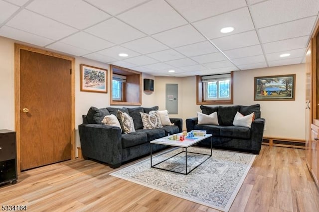 living room with baseboard heating, a drop ceiling, and light wood-type flooring