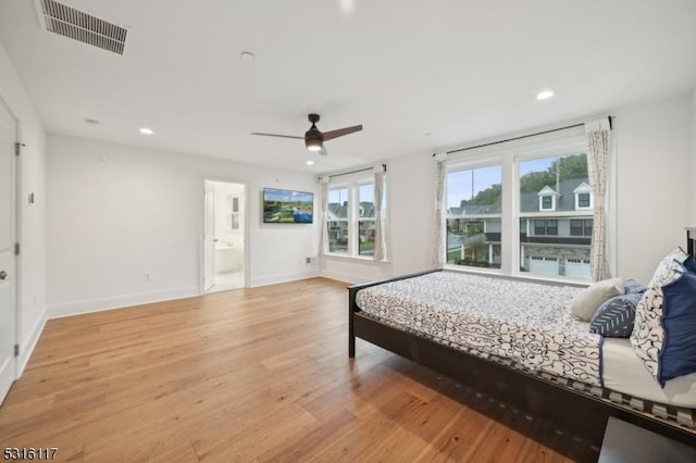 bedroom with ceiling fan, ensuite bathroom, light hardwood / wood-style floors, and multiple windows