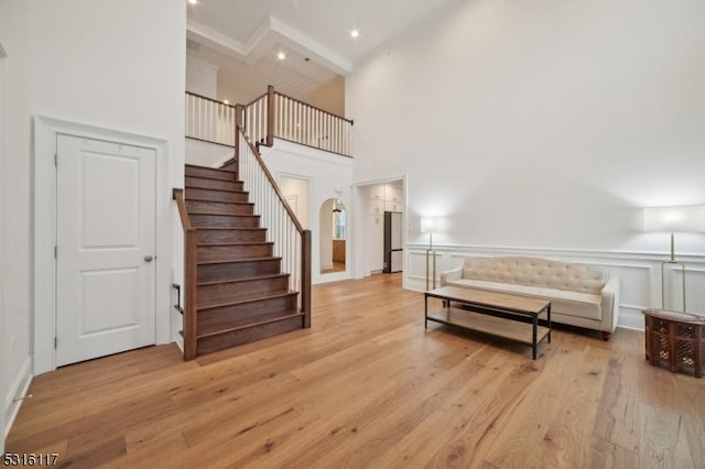 interior space featuring light wood-type flooring, beamed ceiling, and a high ceiling