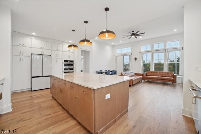 kitchen with a center island, hanging light fixtures, white refrigerator, stainless steel double oven, and white cabinets