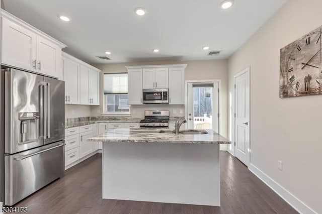 kitchen with sink, light stone counters, a center island, appliances with stainless steel finishes, and white cabinets