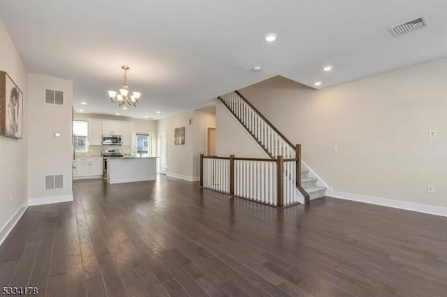 unfurnished living room featuring dark hardwood / wood-style floors and a notable chandelier