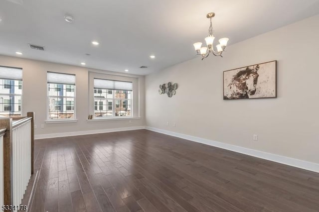 spare room with dark wood-type flooring and an inviting chandelier