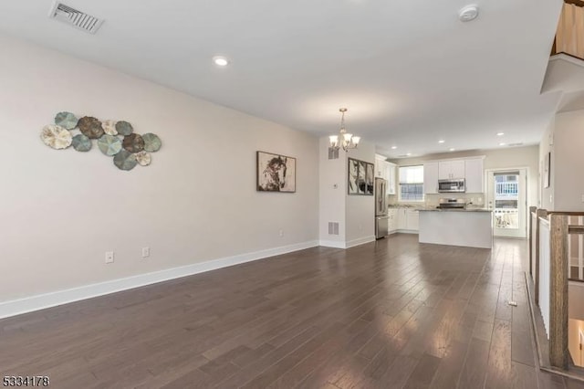 unfurnished living room featuring dark hardwood / wood-style flooring and a notable chandelier