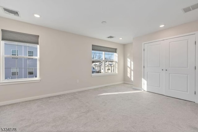 unfurnished bedroom with light colored carpet and a closet