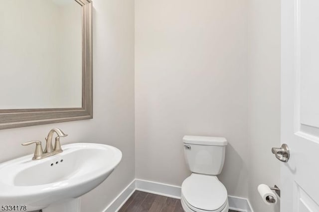 bathroom featuring wood-type flooring, toilet, and sink