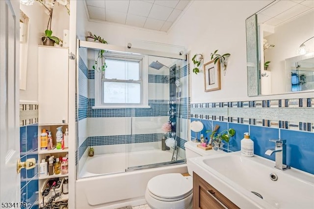 full bath with enclosed tub / shower combo, toilet, vanity, tile walls, and ornamental molding