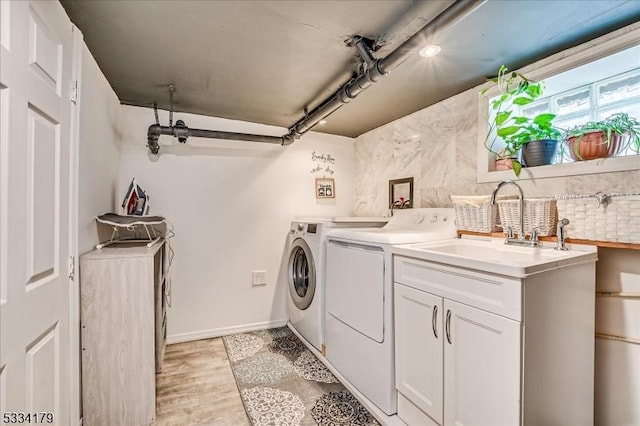 laundry area with laundry area, a sink, baseboards, light wood finished floors, and washing machine and clothes dryer