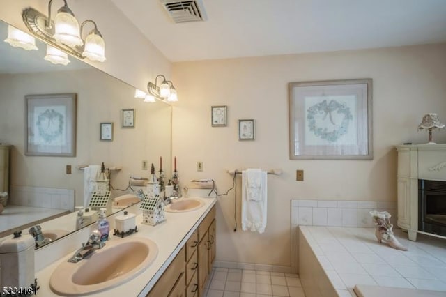 bathroom with tile patterned flooring, vanity, a fireplace, and tiled bath