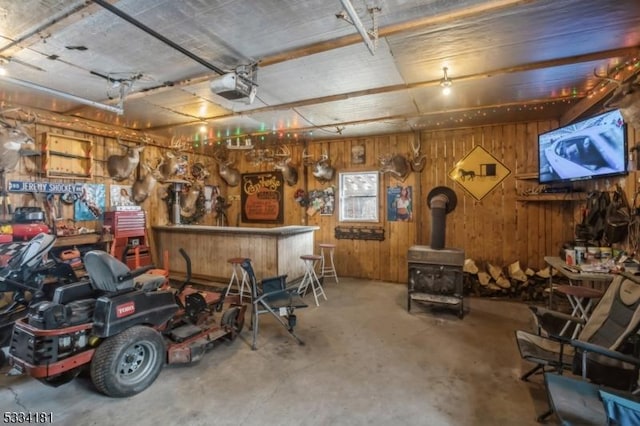 garage featuring a garage door opener, wooden walls, and a wood stove