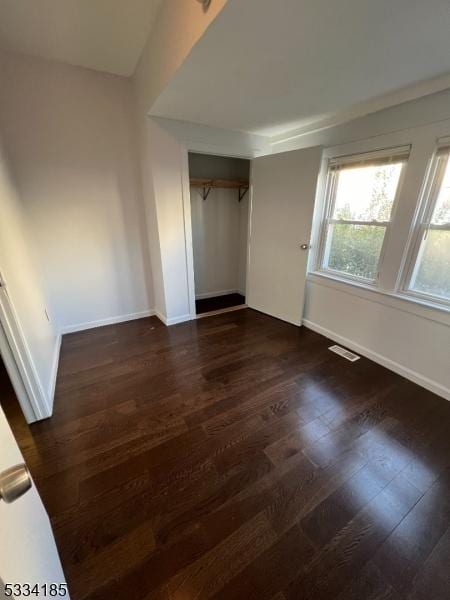 unfurnished bedroom featuring a closet and dark hardwood / wood-style floors