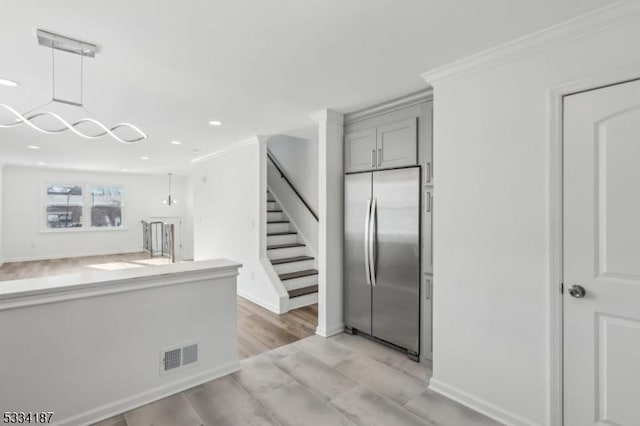 kitchen with gray cabinetry, crown molding, pendant lighting, and stainless steel built in refrigerator