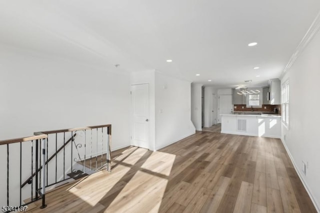 unfurnished living room featuring ornamental molding and light hardwood / wood-style floors