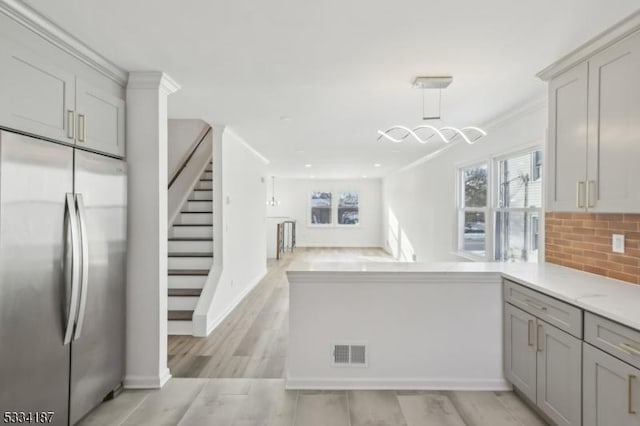 kitchen featuring gray cabinetry, decorative backsplash, stainless steel fridge, and light hardwood / wood-style flooring