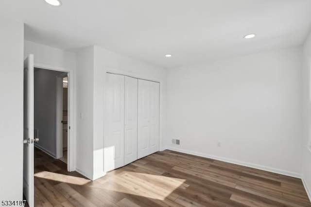 unfurnished bedroom with dark hardwood / wood-style flooring and a closet