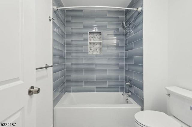 bathroom featuring tiled shower / bath combo and toilet