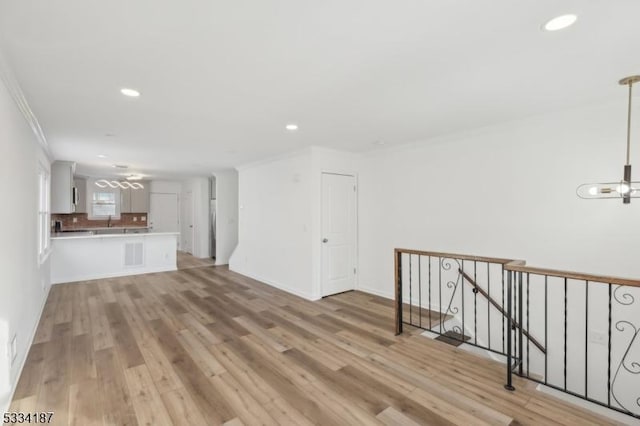 unfurnished living room with crown molding and light wood-type flooring