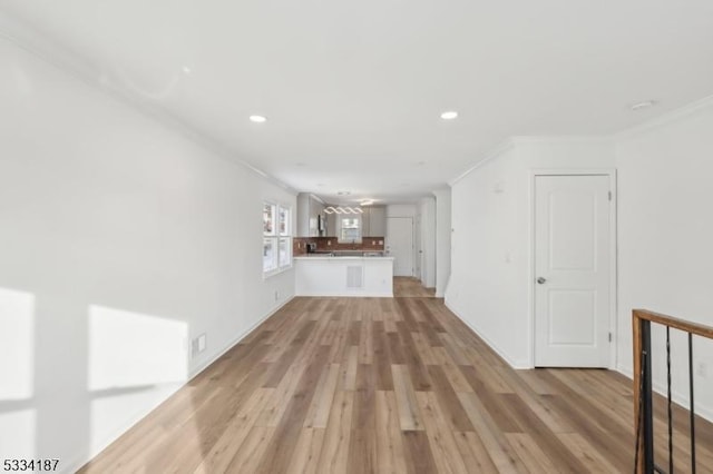 unfurnished living room featuring ornamental molding and light wood-type flooring