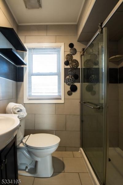 bathroom with vanity, an enclosed shower, ornamental molding, tile patterned floors, and toilet