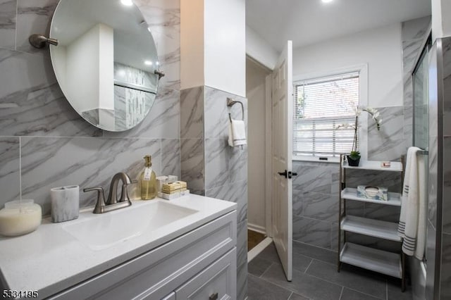 bathroom featuring walk in shower, vanity, and tile walls