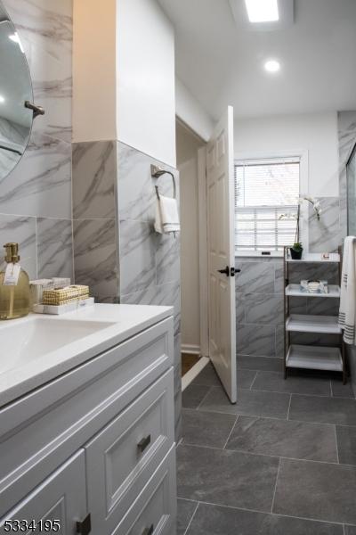 bathroom featuring a shower, tile walls, and vanity