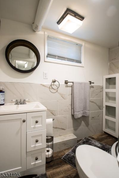 bathroom with tile walls, vanity, hardwood / wood-style flooring, and toilet