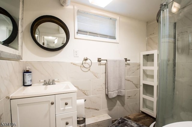 bathroom with walk in shower, tasteful backsplash, vanity, and tile walls