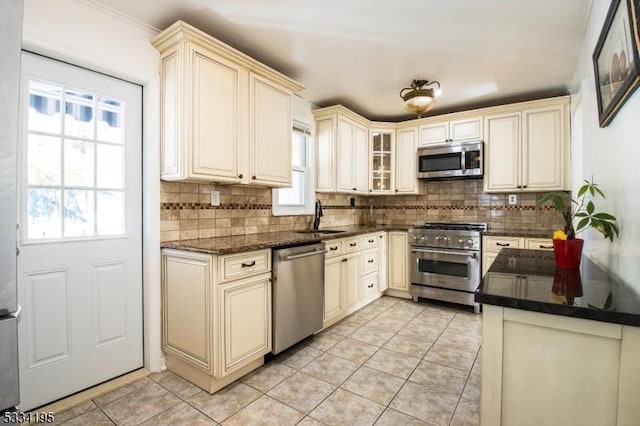 kitchen featuring sink, light tile patterned floors, stainless steel appliances, cream cabinets, and backsplash