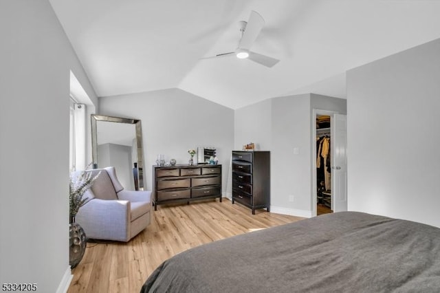 bedroom featuring lofted ceiling, hardwood / wood-style flooring, ceiling fan, a walk in closet, and a closet