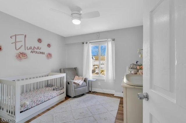 bedroom featuring a crib, ceiling fan, and light hardwood / wood-style floors