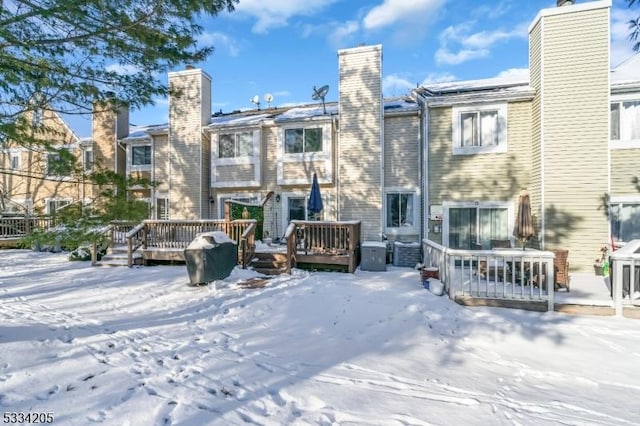 snow covered back of property featuring a wooden deck